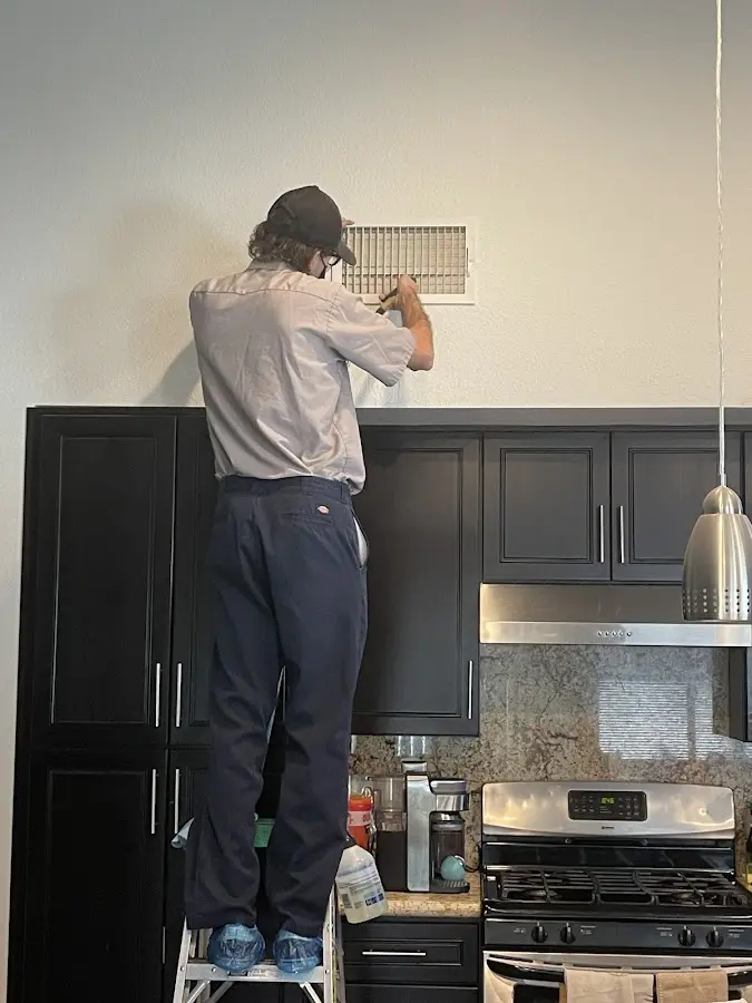 Technician inspecting an air vent during HVAC service in The Village